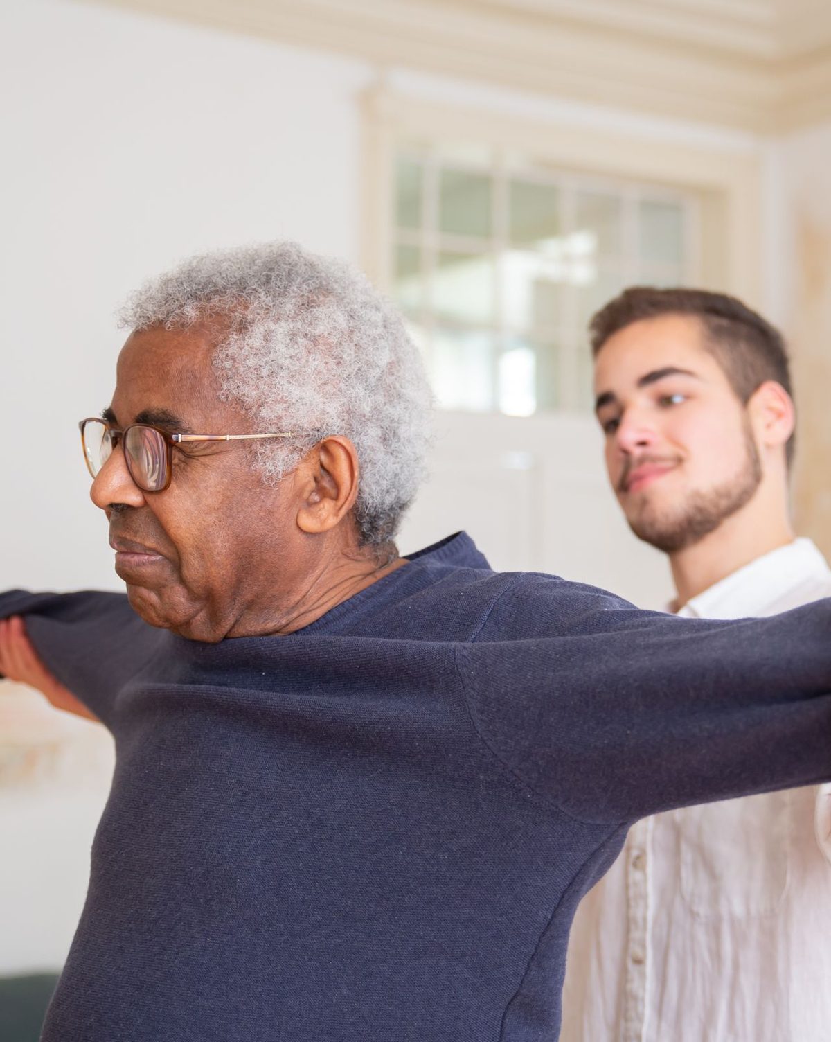 Matt guiding an elderly client through a shoulder and balance exercise at home
