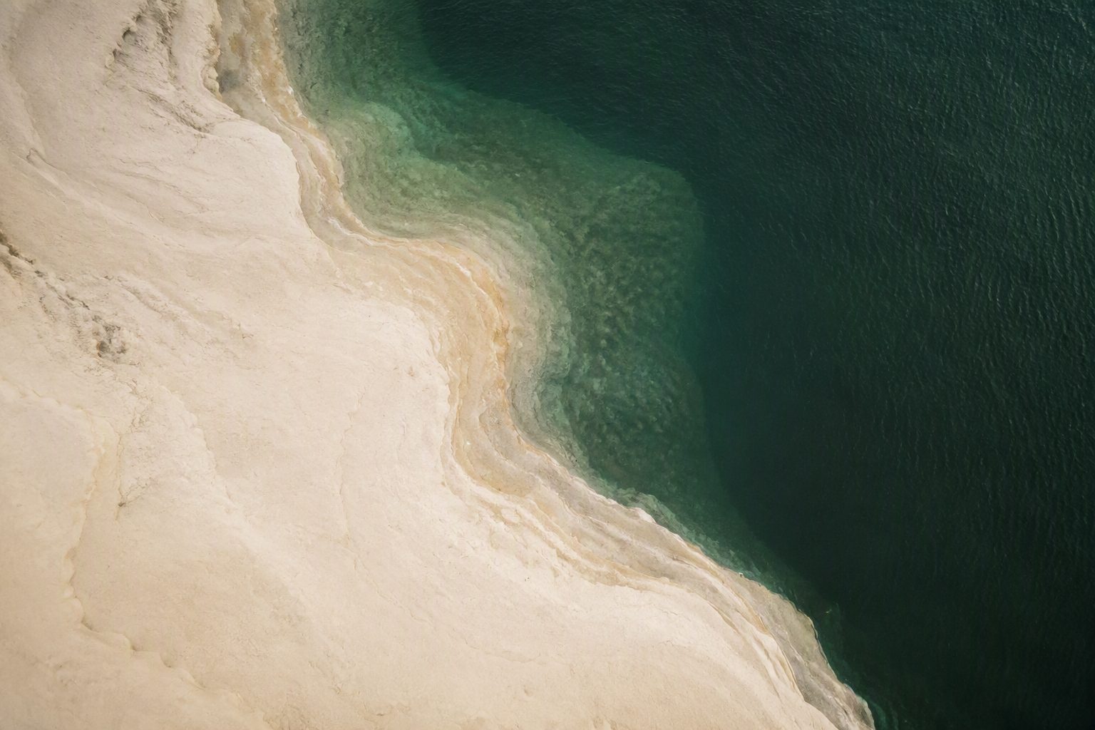 Aerial view of pale sand meeting deep green ocean along the Limestone Coast